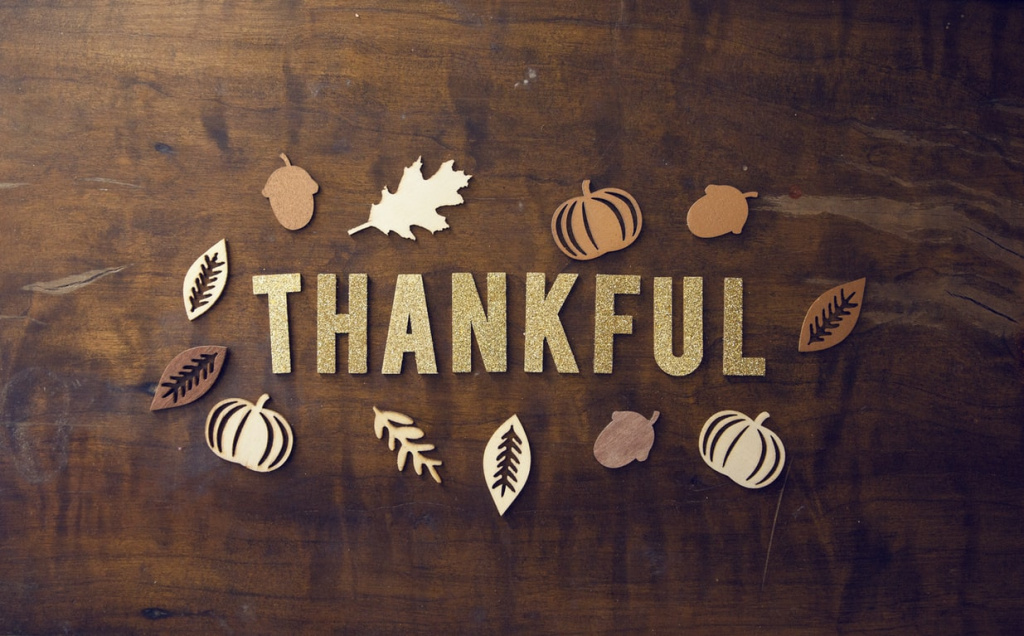 thankful written on wooden background with leaves fall theme